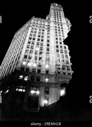 Chicago, Illinois:    c. 1927 A ground level view looking up at the Wrigley Building at night. To the right is the control tower of the Michigan Avenue Bridge. Stock Photo