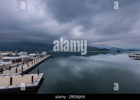 The morning view over Sun Moon Lake Marina in Taiwan is breathtaking, with calm waters reflecting the vibrant sunrise, surrounded by lush green mounta Stock Photo