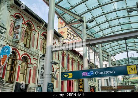 The modern, glass-roofed entrance to Chinatown MRT station in Pagoda Street, Chinatown, Singapore, with traditional old shop houses on the left Stock Photo