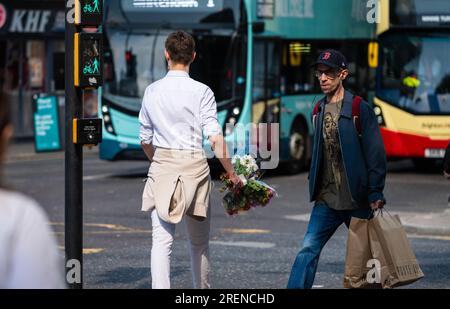Young man walking in a city in Summer, carrying bunch of flowers, UK. Love concept, romantic concept, romance, young love. Bouquet of flowers. Stock Photo