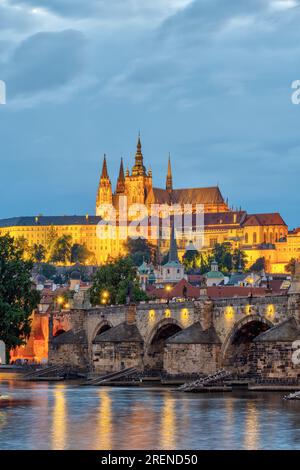 The St. Vitus cathedral with the castle in Prague at night towering above the river Vltava with the famous Charles Bridge Stock Photo