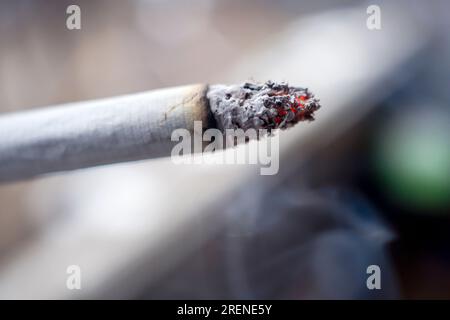 Smoldering cigarette close-up macro shot on blurred background Stock Photo