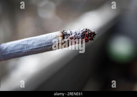 Smoldering cigarette close-up macro shot on blurred background Stock Photo