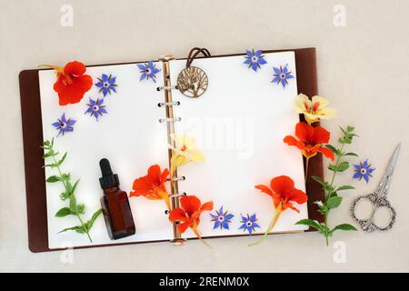 Essential oil preparation for cold and flu remedy with  borage, nasturtium and lemon balm herbs and flowers with old leather notebook. Stock Photo