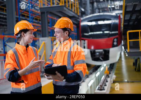 Engineer man and women worker working team together in electric train service depot transport industry factory technician mechanic staff. Stock Photo