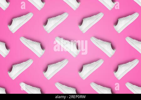 Pattern of white sneakers isolated on pink background. Sportive pair of shoes for mockup. Fashionable stylish sports casual shoes. Stock Photo