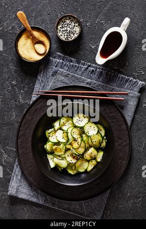 Sunomono, Japanese Cucumber Salad, sliced cucumbers with Asian dressing of soy sauce, rice vinegar, sesame oil and sugar in black bowl on concrete tab Stock Photo