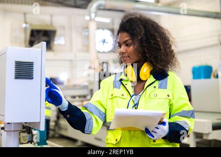 woman worker work control operate CNC wood milling machine in wood furniture workshop. technician staff women working with modern industry machine Stock Photo