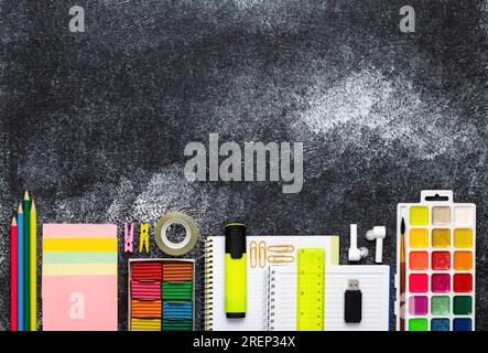 Back to school. Colorful stationery at table background, black chalkboard, flat lay. Education concept. Child's creativity. Space for text. Top view. Stock Photo