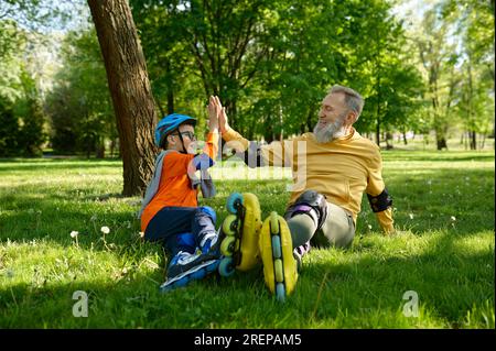 Happy father and son giving high five each other while rest on meadow Stock Photo
