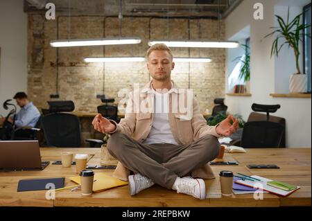 Calm man office worker meditating and breathing at workplace Stock Photo