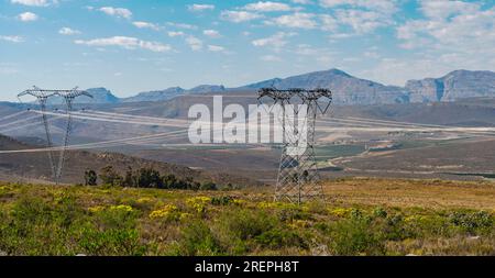 Power lines crossing open scrubland with light reflection on the power lines Stock Photo