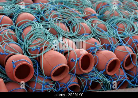 Terracotta octopus pot traps in nets. Clay pot fishery industry in Spain Stock Photo