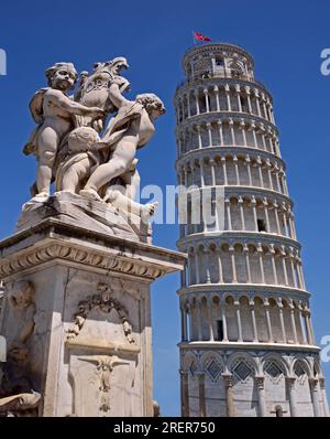 Pisa, Italy - May 21, 2016: The famous Leaning Tower of Pisa with a nearby statue on a clear blue background. Stock Photo