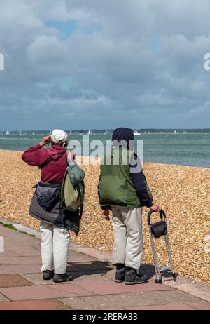 older couple taking a bracing walk along the beach on the isle of wight uk Stock Photo