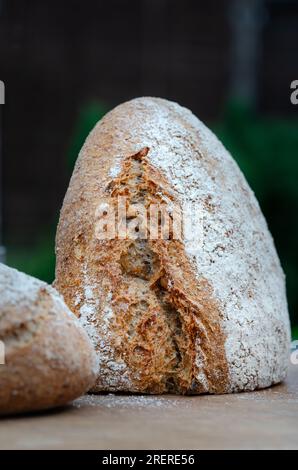 Sliced wholemeal bread is displayed on a wooden board that has a battered texture. Stock Photo