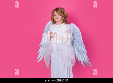 Valentine's day. Blonde cute child with angel wings on a pink red studio background. Happy angel child. Stock Photo