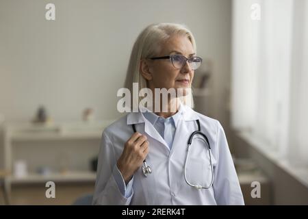 Serious senior medical practitioner in glasses and uniform looking away Stock Photo