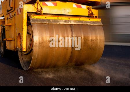 Asphalt road roller with heavy vibration roller compactor at road construction site. Stock Photo