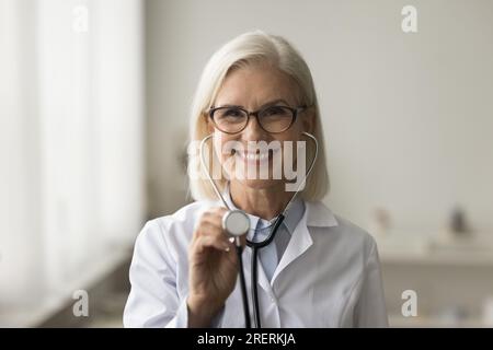 Happy mature medical practitioner using stethoscope head shot portrait Stock Photo