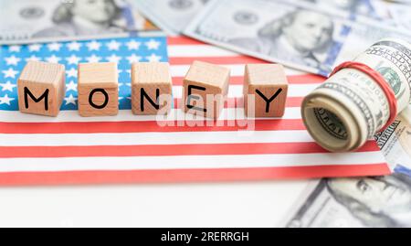 Word MONEY written by wooden cubes with american flag and american dollar bills. Stock Photo