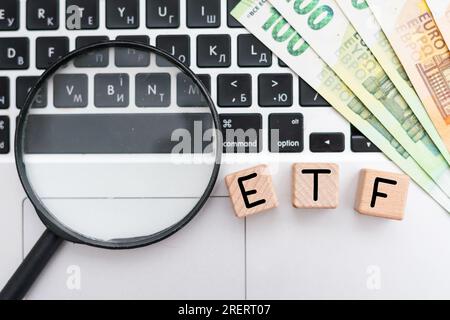 ETF - text on wooden cubes on a cold grey light background with stacks coins Stock Photo
