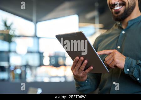 Smiling young business man holding tablet in hands at work. Close up, copy space Stock Photo