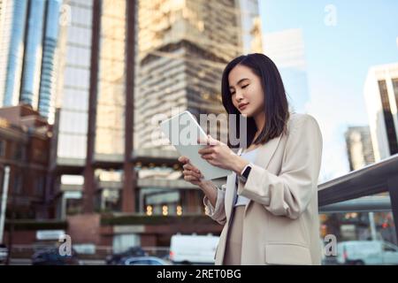 Young Asian business woman professional standing in city using digital tablet. Stock Photo