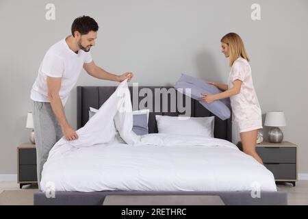 Couple changing bed linens in room. Domestic chores Stock Photo