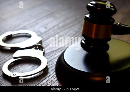 Judge’s gavel and block with handcuffs on a dark wooden table Stock Photo