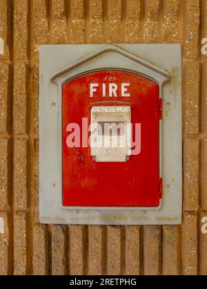 Vintage fire alarm red pull box mounted to the side of a municipal building in a city. background. Close up. Stock Photo
