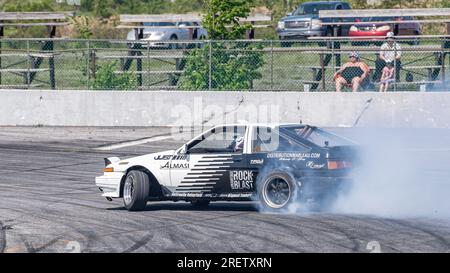 Car drifting auto racing event action with smoking tires - burning tires on the track in motion. Sanair Superspeedway, Canada, Quebec Stock Photo