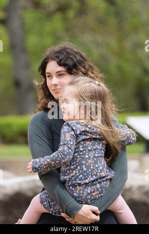 a mother holding her daughter at a park Stock Photo