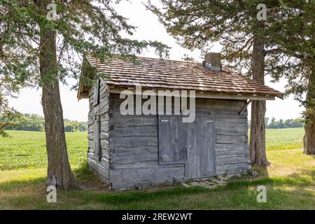 Sunny landscape view of a 19th century log cabin on the prairie in midwestern United States Stock Photo