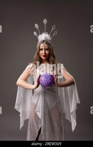 Gentle fairy in white translucent dress with magic ball in her heands Stock Photo