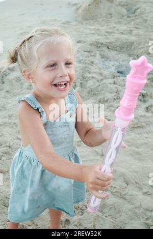 Cheerful cute toddler with container of soap bubbles laughing and enjoying vacation in summer Stock Photo