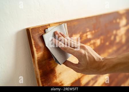 Scrubbing wood panel with sandpaper Stock Photo