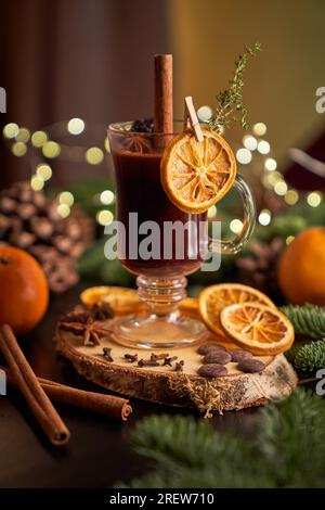 Glass of alcoholic mulled wine served with cinnamon stick and dried orange slice placed on blurred background in light room Stock Photo