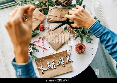 https://l450v.alamy.com/450v/2rew71t/top-view-of-crop-anonymous-female-with-scissors-cutting-ribbon-while-preparing-christmas-presents-on-table-with-decorations-2rew71t.jpg