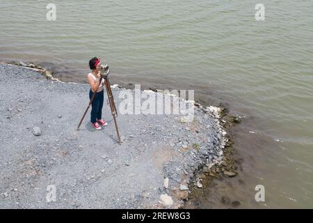 Pretty Asian female surveyor or engineer worker working with theodolite transit equipment at outdoor construction site . Stock Photo