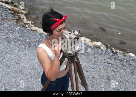 Pretty Asian female surveyor or engineer worker working with theodolite transit equipment at outdoor construction site . Stock Photo