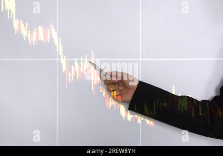 A professional man, donned in a fitted business suit, as he intently point towards an upward trending stocks chart highlighted on a digital screen. Stock Photo