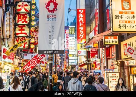 View along Dotonbori, early evening, busy with people. Foreground