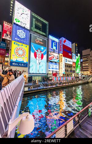 View from the Ebisu bridge at night of the famous Glico Running Man neon light display at Dotonbori, Osaka, the sign abstractly reflected in the river Stock Photo