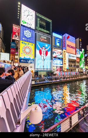 View from the Ebisu bridge at night of the famous Glico Running Man neon light display at Dotonbori, Osaka, the sign abstractly reflected in the river Stock Photo