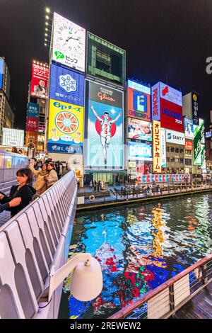 View from the Ebisu bridge at night of the famous Glico Running Man neon light display at Dotonbori, Osaka, the sign abstractly reflected in the river Stock Photo