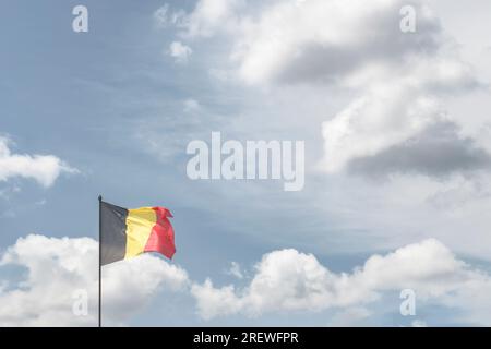 Belgian National Day. The national flag of the Kingdom of Belgium against the background of clouds in the sky. copy space Stock Photo