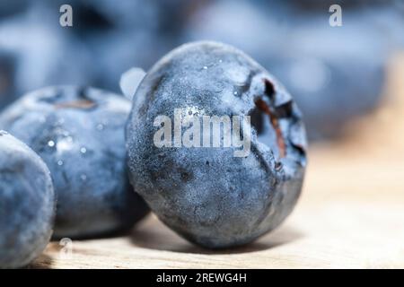 wet ripe juicy and tasty blueberries on a wooden table, blueberry berries are covered with water drops, wet berries can be used to eat raw or make des Stock Photo
