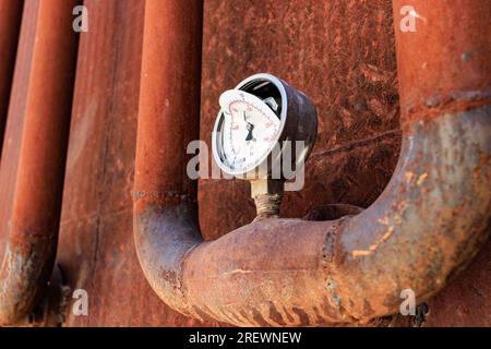 A broken rusty pressure gage on a rusty pipeline Stock Photo