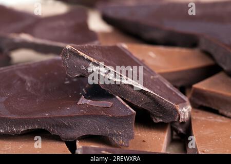 several pieces of broken chocolate of different types, milk and bitter chocolate together broken into pieces with crumbs Stock Photo